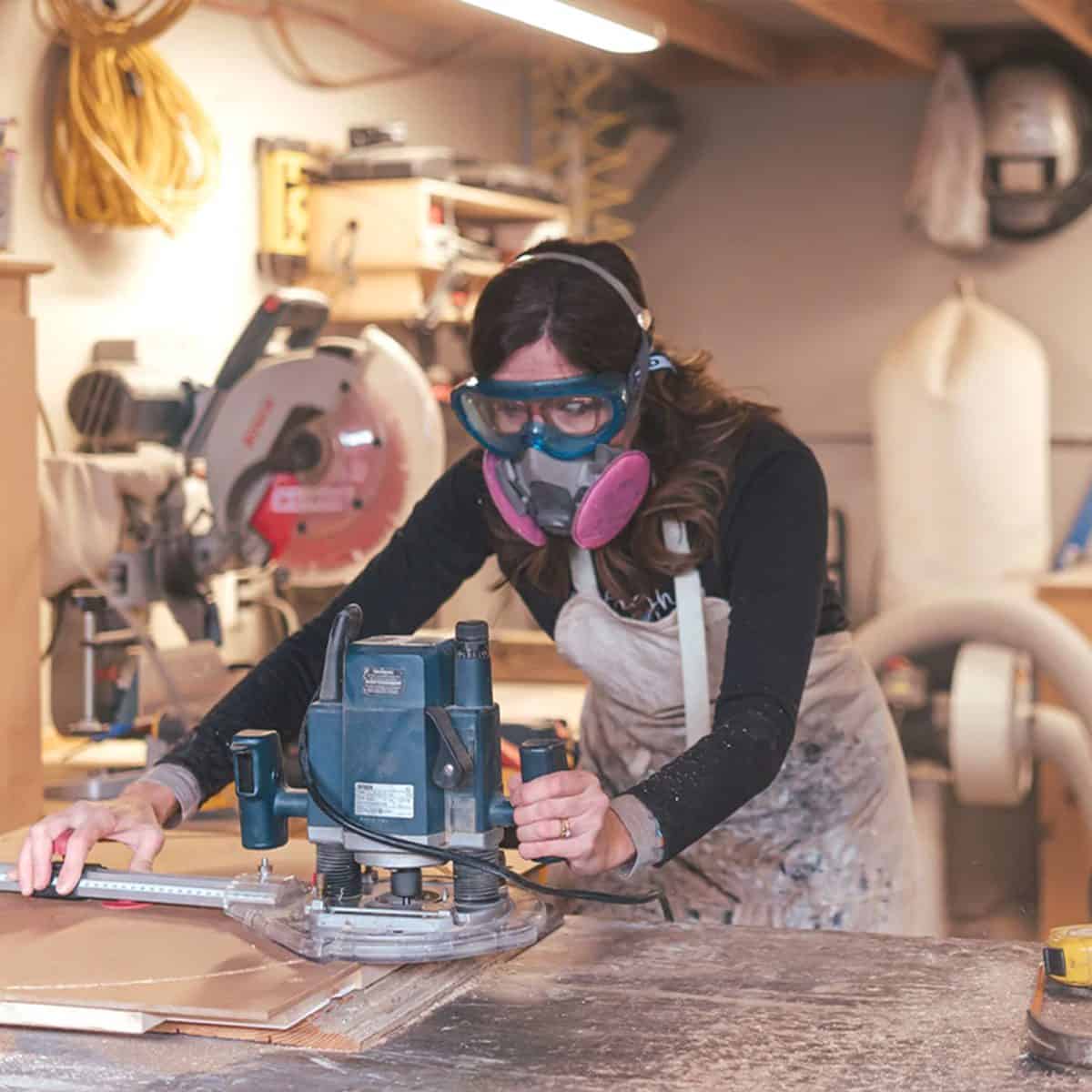 Christa Ker using a saw to cut a large piece of wood.