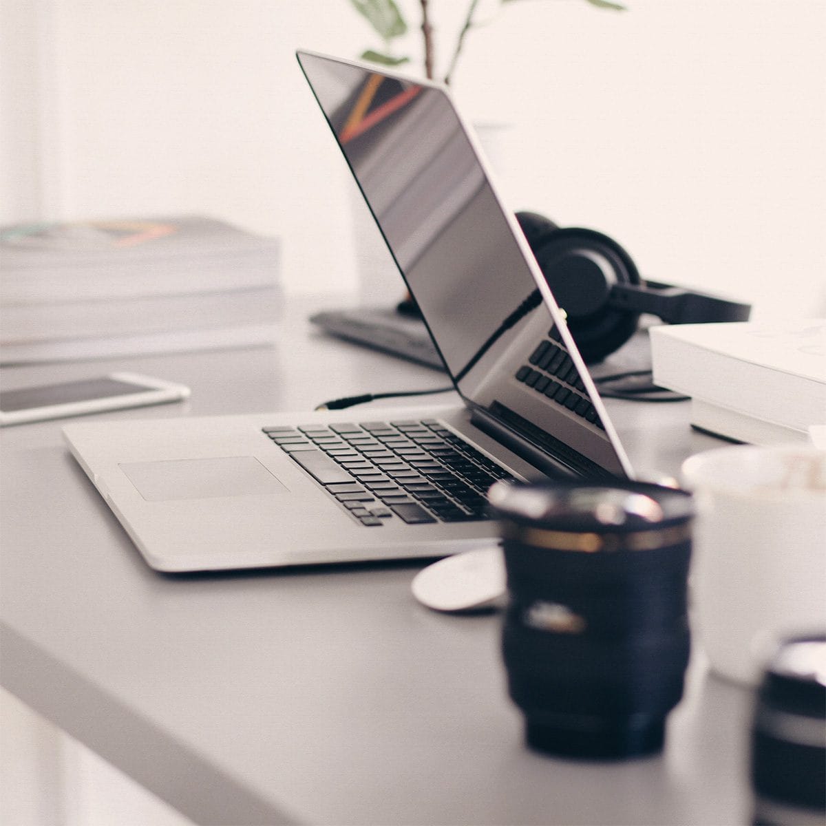 A MacBook laptop slightly closed on a clean desk.
