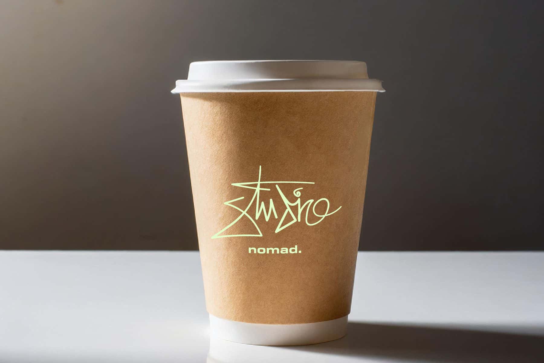 Studio Nomad logo on a paper coffee cup.