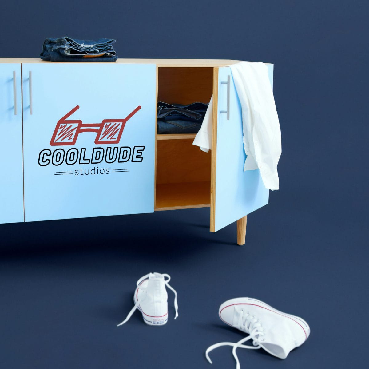 Cool Dude Studio logo on a low cupboard with the door open.